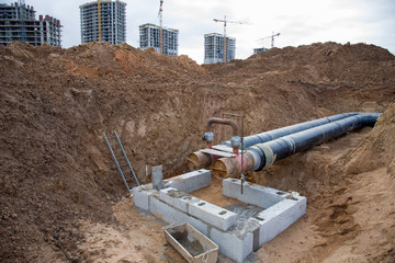 Laying heating pipes in a trench at construction site. Installation underground storm sewer pipes ...