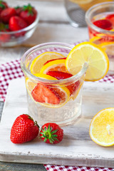 Refreshing homemade lemonade with fresh strawberry, lemon and ice. Healthy cold drink, low calories. Tasty cool summer beverage. Wooden white background, two glasses