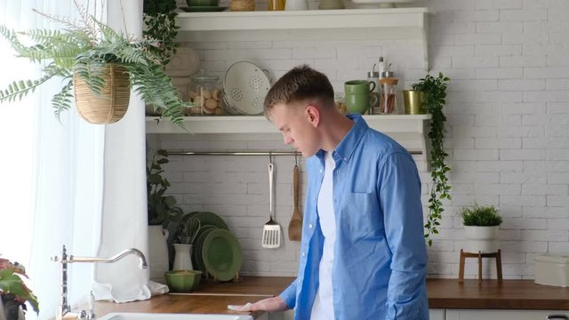 Man checking a dust level on a furniture surface in a kitchen with a napkin. A lot of dust in the kitchen and non-compliance with cleanliness standards
