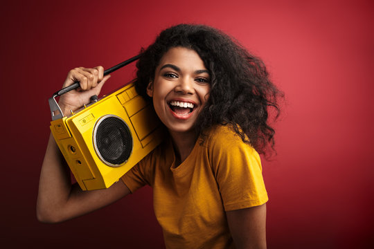 Image of african american woman laughing and holding vintage boombox