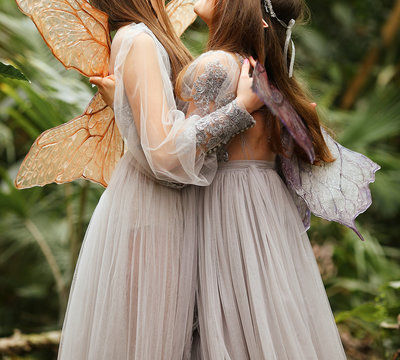 Magical fabulous photo shoot. Two elfs with transparent wings and long blond hair. Beautiful young girls in a silver-purple dress enjoys nature in a botanical garden. Magic and magic. Special effects