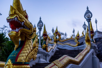 Detail of a dragon sculpture nexto to some steps in a temple in Krabi, Thailand, shot at sunset