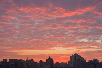 Bright multi-colored clouds over the city at sunrise