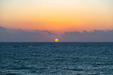 When the sun rises by the horizon of Tulum, illuminates all the clouds and the water of the caribbean sea with his orange light