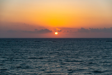 When the sun rises by the horizon of Tulum, illuminates all the clouds and the water of the caribbean sea with his orange light