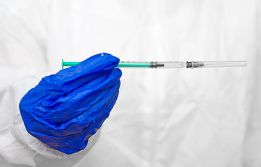 Human in biohazard suit holding syringe.