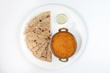 Handmade flat bread chapati and dal tadka fry in brass bowl pan on white plate and background - obrazy, fototapety, plakaty