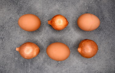 Aneinander gereiht: braune Bio-Eier und Ziebeln