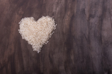 Grains of rice are folded in the heart on an artistic dark background