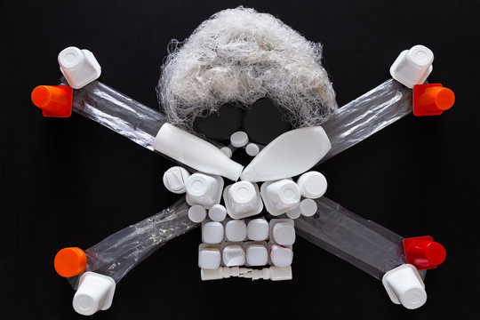 Concept of environmental pollution with plastic waste. Top view of a jolly roger or skull and crossbones symbol made with different plastic objects.