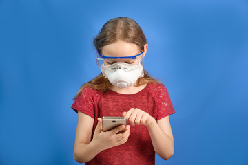 Young long-haired girl in a protective medical mask on a blue background, place for text