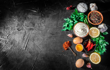 Mayonnaise with eggs, parsley and garlic cloves on dark background