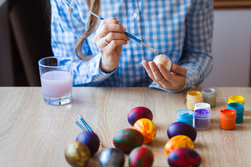 Holidays, handmade and creation concept - Girl draws on Easter egg, close-up.