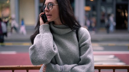 Attractive female blogger in trendy outfit making international conversation with friend after shopping day in metropolitan downtown, millennial hipster girl in eyeglasses typing text message via cell