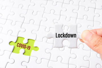 The lockdown word on white jigsaw puzzle go to replace COVID-19 word on green gap - idea answer concept.