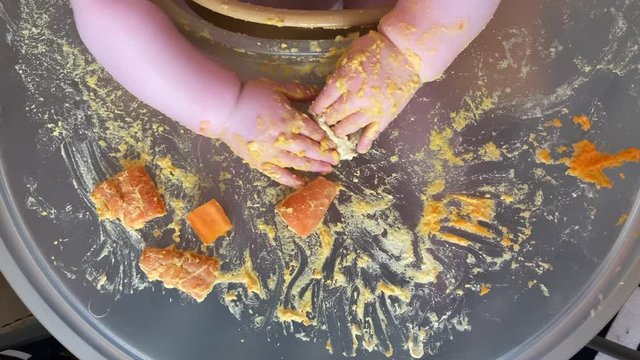 hands of a baby making a mess at meal time during baby led weaning