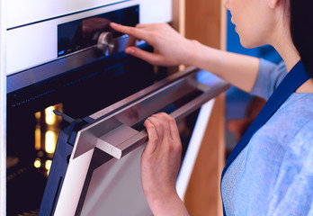 Obraz premium Beautiful young woman checking how her cake is doing in the oven