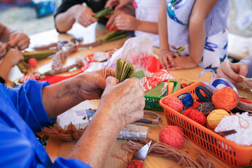 Creative items and crafts for children at home on the table. Paints and brushes, scissors, thread and scraps of fabric - the hands of the child and the parent in the background.