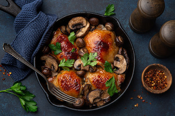 roasted  chicken thighs with mushrooms on cast iron  pan