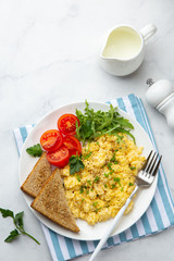 scrambled eggs, tomatoes, toasted bread and greens  for breakfast
