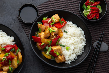 Sweet ad sour chicken served with steamed rice in black bowl