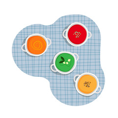 Healthy cuisine set of white ceramic pots of various cream soups - tomato, carrot, broccoli, pumpkin cream soup on blue tartan table cloth background. 