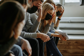 side view on people in medical masks, they sit in hospital, waiting for their appointment to doctor. epidemic, flu, sickness, protection, coronavirus concept
