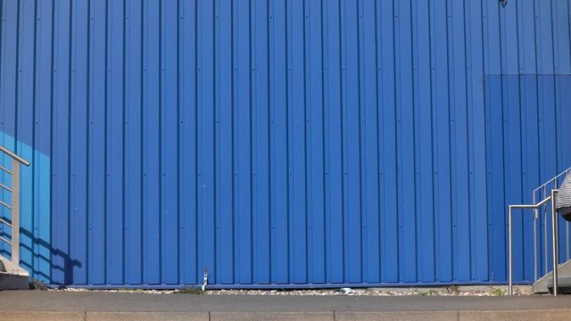 Cool man / athlete wheelies with BMX Bike next to blue urban building / Slowmo / Outdoor Extreme & Action & Fun Sports