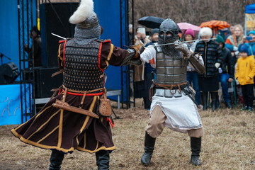 battle reconstruction. Men in armor fight with swords against the background of the audience