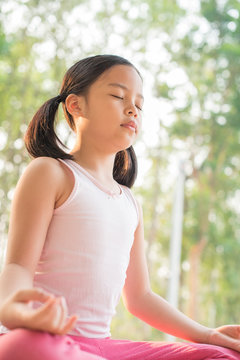calmness and relax, female happiness.Horizontal, blurred background. little asian girl meditates while practicing yoga. freedom concept. calmness and relax, child happiness. toned picture healthy life