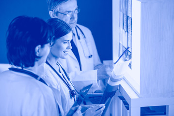 Group of doctors examining x-rays in a clinic, thinking of a diagnosis