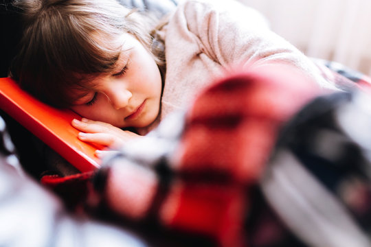 Girl reading a book lying on the couch during quarantine. Stay home to stop the spread of Coronavirus
