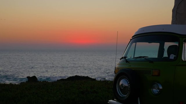 Spectacular sunset over the Atlantic Ocean with a retro camper van in Cabo de Roca. Green combi T1 Westfalia .
