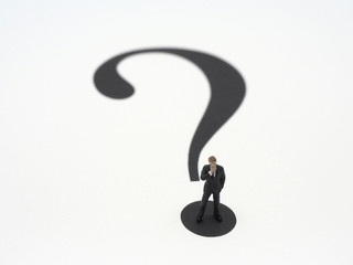 A miniature businessman riding on the question mark.Question concept image.