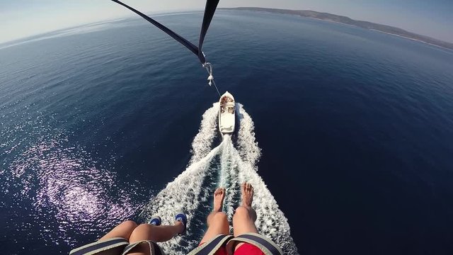 Parasailing landing approach speed motorboat POV young couple legs over blue sea. Amazing Adriatic vacation holiday honeymoon in Croatia
