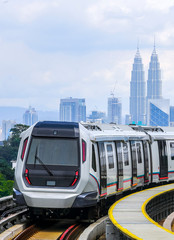 Obraz premium Malaysia Mass Rapid Transit (MRT) train with a background of Kuala Lumpur cityscape. People commute with MRT as transportation to work, school, travel, and shopping.