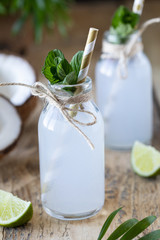 Two bottles of coconut water on a wooden table.
