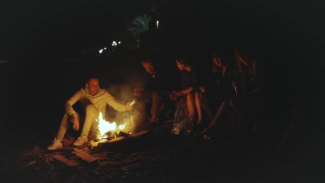 Group of friends having fun near the campfire on the beach near the sea at night, rapid video, slow motion, full hd