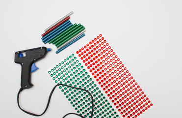 Concept of glue gun with colorful glue sticks on white background. Home hobbies crafts