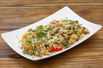 stewed vegetables with rice on a plate on a wooden background