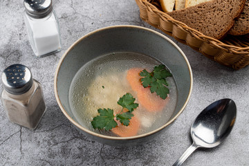 A bowl of hot chicken broth with carrots, a part of kids menu