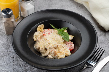 A portion of farfalle alfredo with creamy sauce and chicken breast, decorated with grated parmesan cheese