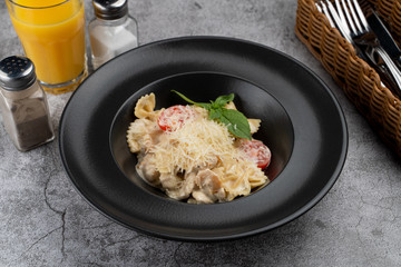 A portion of farfalle alfredo with creamy sauce and chicken breast, decorated with grated parmesan cheese