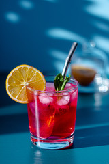 pink cocktail on a blue background with lemon