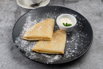 Plain thin crepes with butter and sour cream with a cup of tea and a teapot