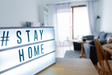 Fototapeta na wymiar Lightbox sign with hashtag; Stay Home against the background of the interior of the apartment.