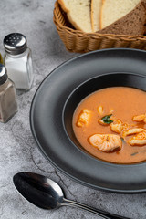 Hot and spicy tomato seafood soup with salmon, prawns and squids, close up