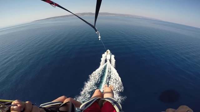 Amazing Adriatic vacation in Croatia destination. Parasailing over Adriatic sea young couple descending to speed motorboat white foam on crystal blue sea