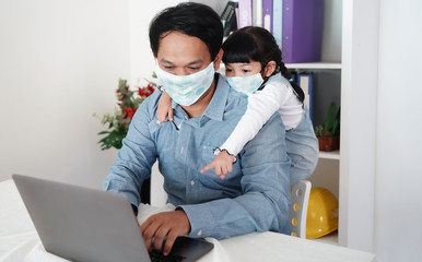 Businessman father and daughter wear surgical mask while working at the computer. Business working from home and prevention from Covid-19. 