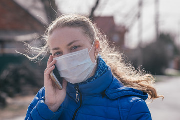 Caucasian girl on sick leave in medical protective mask, calls on the phone, calls a taxi. Seasonal...